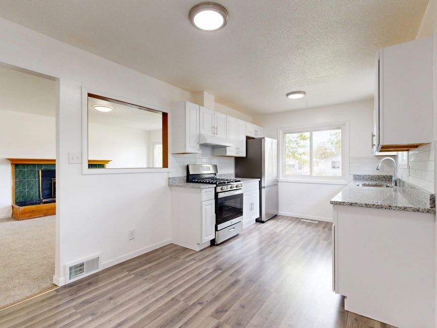 Newly renovated kitchen with white cabinets and hardwood floors.